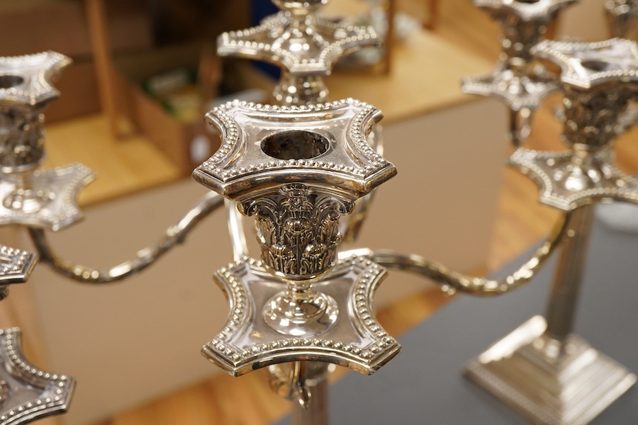 A garniture of 19th century silver plated Corinthian column candelabra, comprising a pair of two branch, three light candelabra and matching four branch, five light candelabrum, with detachable acanthus leaf capped scrol